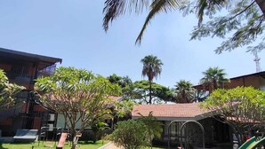 Un patio con palmeras, un parque infantil y un edificio de techo rojo.