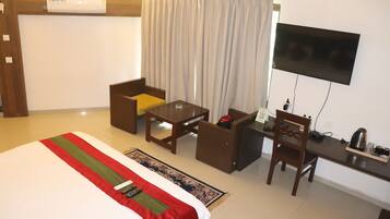 Habitación de hotel con cama, escritorio, silla, televisor y cafetera.