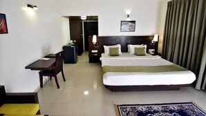 Una habitación de hotel con cama, mesitas de noche, escritorio, silla y alfombra.