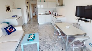 En kompakt bolig med tekøkken, spiseplads og fjernsyn monteret på væggen.
