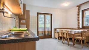 Una cucina con lavello, pensili in legno e un'area pranzo con sedie e tavolo.