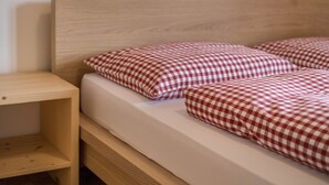 Un letto con testiera in legno e biancheria a quadri.