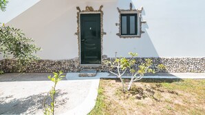 Un bâtiment avec un mur en pierre, une porte noire et une petite fenêtre.