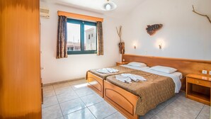A bedroom with a bed, a wooden wardrobe, a window with curtains, a bedside table, and a wall-mounted light fixture. - Studio 'Mirage Arillas Studio Type A8' with Sea View, Pool & Wi-Fi (corfu)