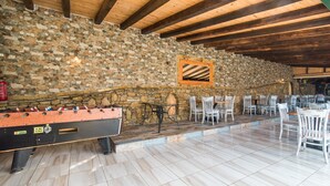 A stone-walled room with a foosball table, white chairs, and a wooden ceiling. - Studio 'Mirage Arillas Studio Type A8' with Sea View, Pool & Wi-Fi (corfu)