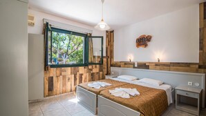 A bedroom with two beds, a wooden wall panel, a window with a view, a ceiling light, and a wall-mounted sign. - 'Mirage Arillas Studio Type A9' next to Beach with Balcony, Shared Pool & Wi-Fi (corfu)