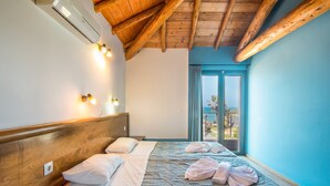 Ein Hotelzimmer mit Holzboden, einem Bett mit Kopfteil, Nachttischen und Blick durch eine Tür.