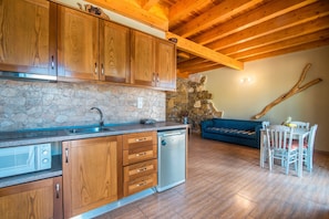 A kitchen with wooden cabinets, a stone wall, a built-in dishwasher, and a dining area with a table and chairs.