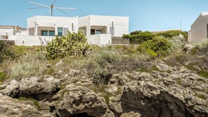 A modern building with a flat roof, large windows, and a wind turbine.