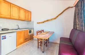 Une cuisine compacte avec des meubles en bois, une table à manger, un canapé et une branche décorative accrochée au mur.