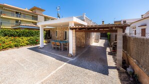 A covered patio with a table and chairs, a stone wall, and a fence.