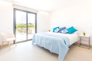Une chambre à coucher avec un lit, une chaise, une table de chevet et une vue sur l’extérieur, accessible par une porte coulissante.