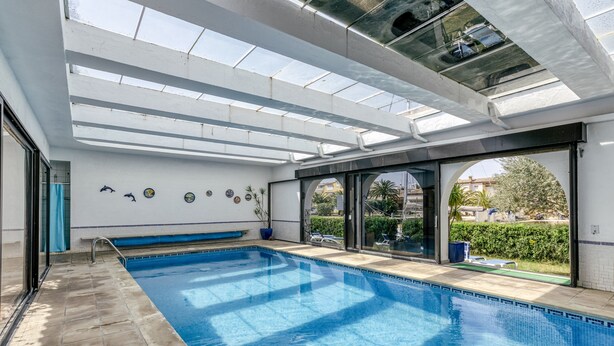 A swimming pool with a glass ceiling, a bench, and a view of the outside. - Apartment 'ART-Apartamentos Revilla Tacke E' with Shared Pool & Wi-Fi (Empuriabrava)
