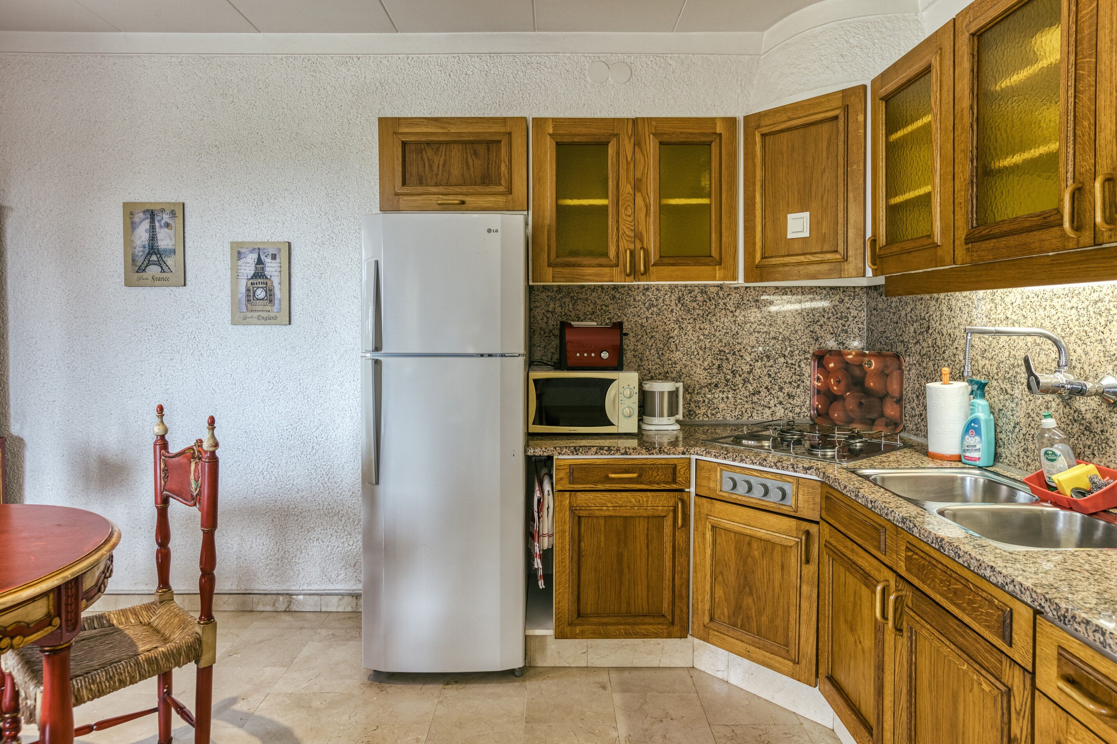 A kitchen with wooden cabinets, a refrigerator, a microwave, a stove, and a sink.