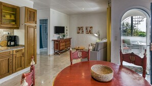 A spacious kitchen with wooden cabinets, a dining table with chairs, a television, and a view through an archway to an outdoor seating area. - Apartment 'ART-Apartamentos Revilla Tacke E' with Shared Pool & Wi-Fi (Empuriabrava)