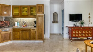 A kitchen with wooden cabinets, a granite countertop, a stove, and a dining area with a table and chairs. - Apartment 'ART-Apartamentos Revilla Tacke E' with Shared Pool & Wi-Fi (Empuriabrava)
