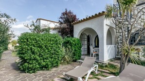 A courtyard with stone flooring, a white building with arches, and two lounge chairs. - Apartment 'ART-Apartamentos Revilla Tacke E' with Shared Pool & Wi-Fi (Empuriabrava)