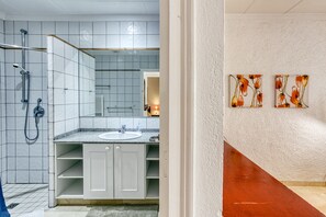 Un baño con ducha, lavamanos y armarios de almacenamiento.