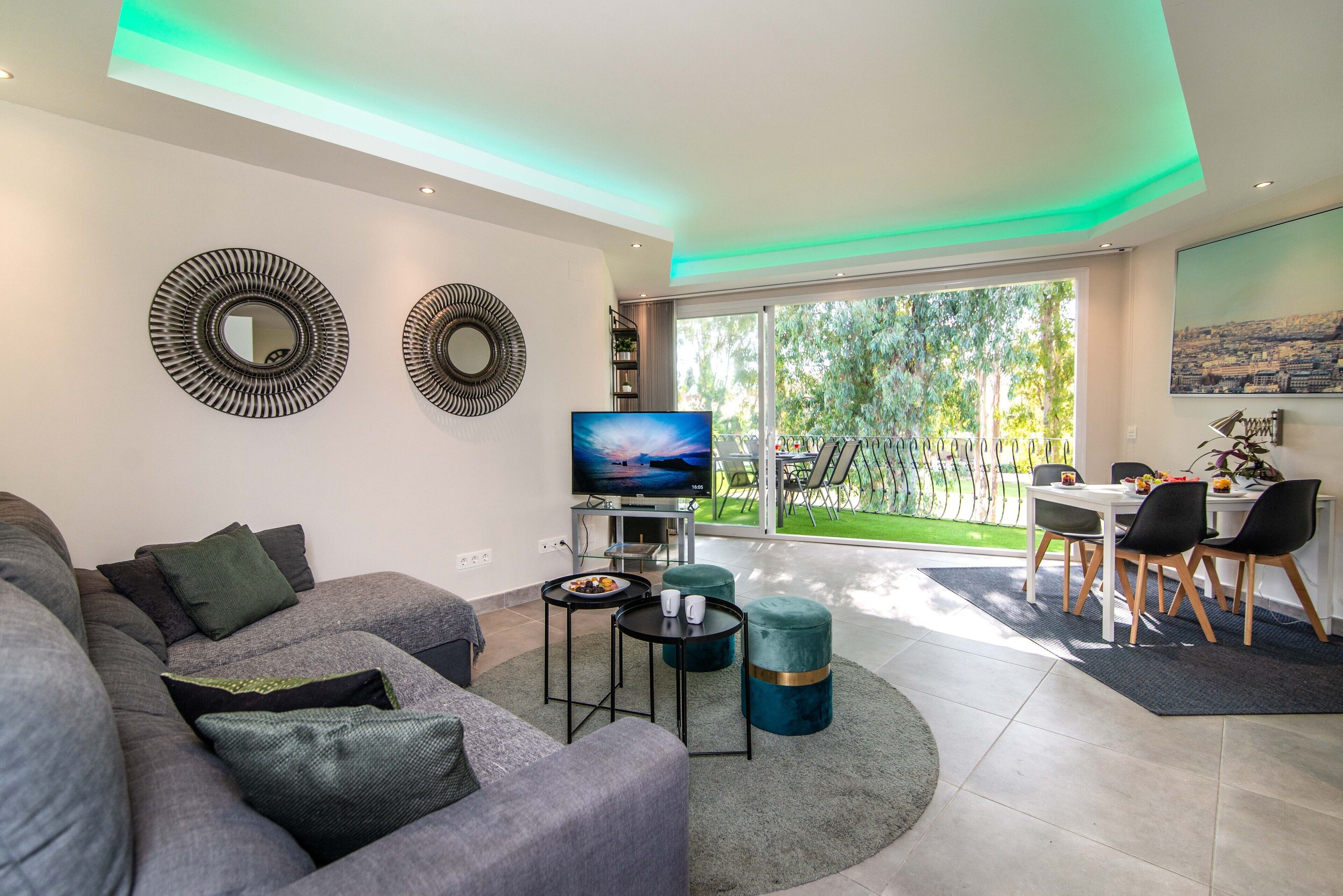 Una sala de estar moderna con un sofá, un televisor y un comedor con sillas y una mesa.