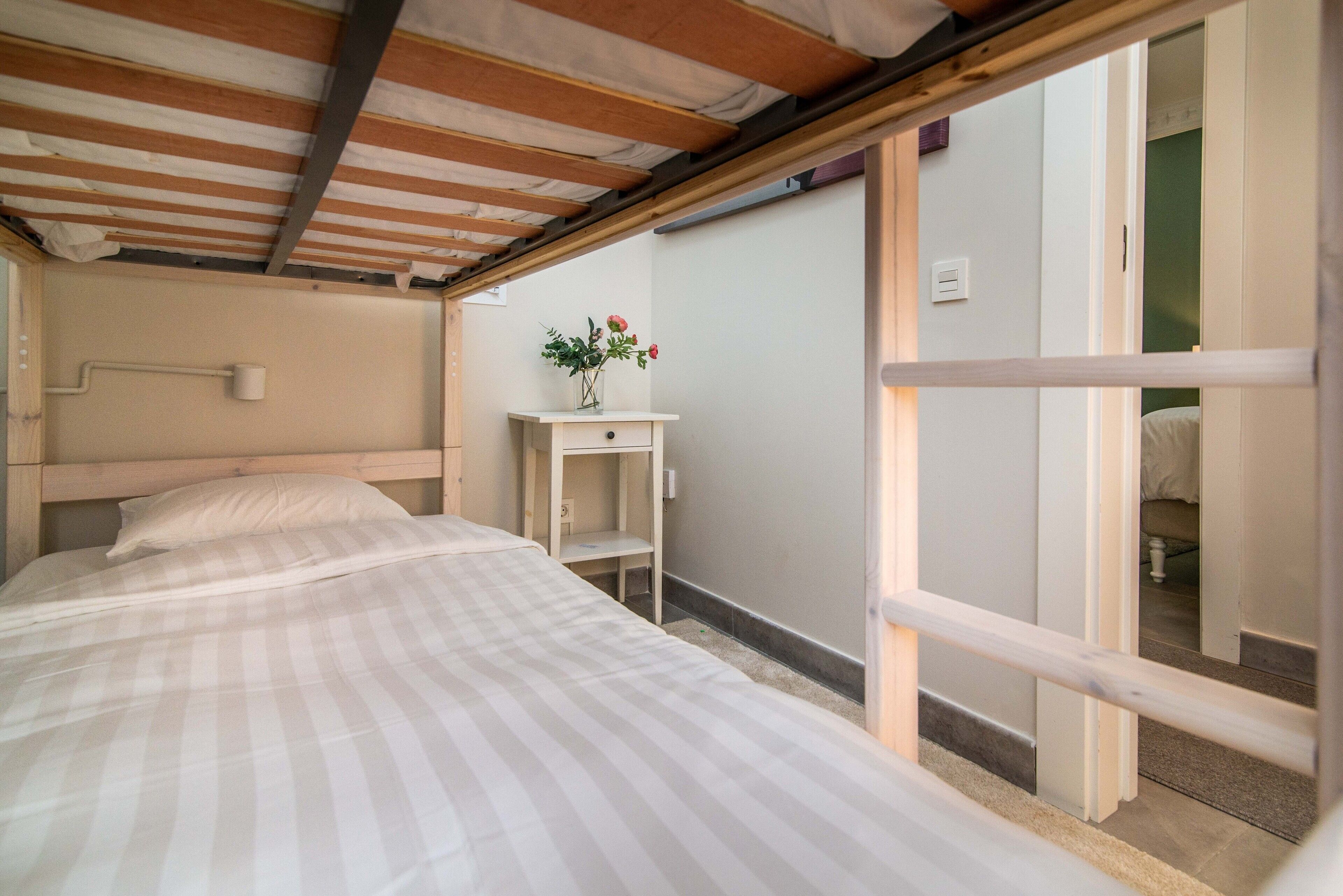 Una camera da letto con un letto, un tavolino con un vaso di fiori e una vista attraverso una porta aperta.