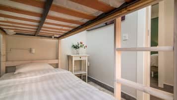Una camera da letto con un letto, un tavolino con un vaso di fiori e una vista attraverso una porta aperta.