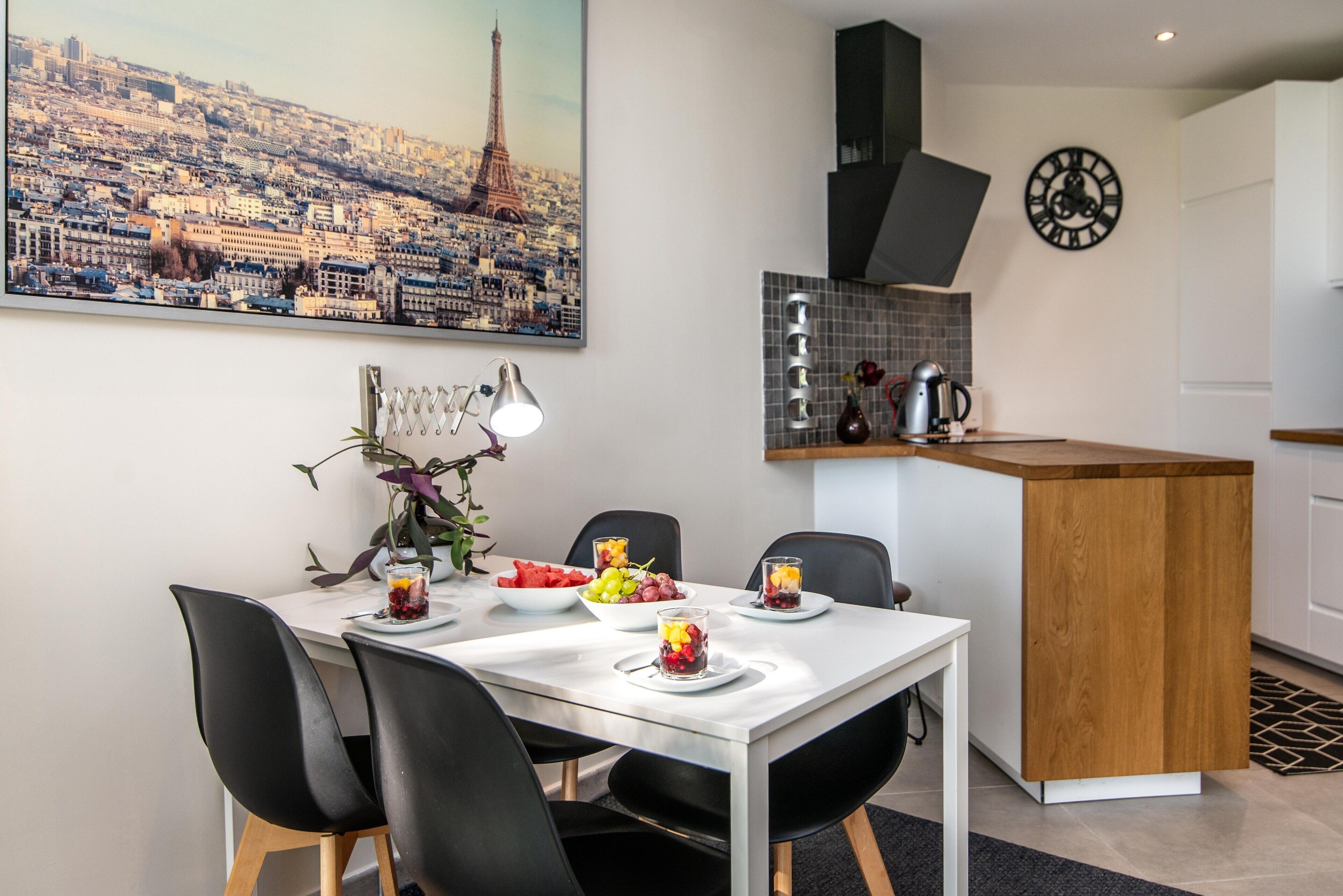 Una cucina moderna con un'isola centrale, un tavolo da pranzo con sedie e un quadro raffigurante un panorama urbano.