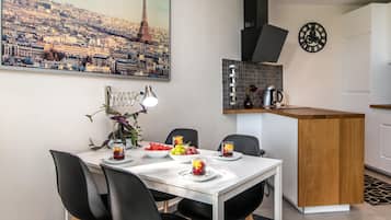 Una cucina moderna con un'isola centrale, un tavolo da pranzo con sedie e un quadro raffigurante un panorama urbano.