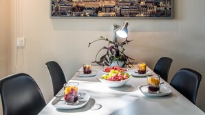 Una mesa de comedor con platos de fruta, un florero con una planta y una lámpara.