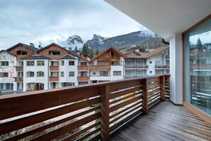 Ein Balkon mit Holzbalkonen, der auf eine Reihe von Gebäuden mit Balkonen und einer Bergkulisse blickt.