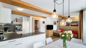 A modern kitchen with white cabinets, a built-in microwave, and a dining area with a table and chairs.