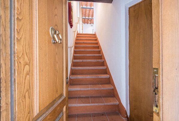 A wooden staircase leading to a room with a red curtain. - Apartment "Casa di Franca a San Galgano" in Historical Centre (CHIUSDINO)