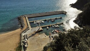 Un port de plaisance situé sur la côte, avec des bateaux amarrés, une jetée et une plage.
