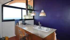 Une cuisine dotée d’un grand îlot central, de deux suspensions lumineuses, d’une fenêtre offrant une belle vue et d’un tabouret de bar.