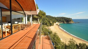 Une terrasse avec des sièges extérieurs donnant sur une plage et l’océan.