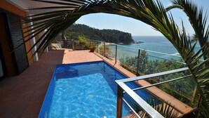 Une piscine sur le toit offrant une vue dégagée sur l’océan et un paysage montagneux.