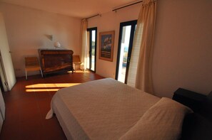 A bedroom with a bed, a dresser, a chair, and a window with curtains.