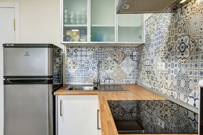 A kitchen with a stainless steel refrigerator, a sink, and a wooden countertop.
