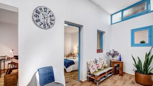 A modern living room with a round wall clock, a blue chair, a wooden coffee table, and a potted plant. - Vacation Home 'Casa Bene' with Mountain View, Wi-Fi and Air Conditioning (Guimar)