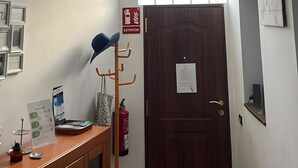 Une pièce comprenant un bureau en bois, un extincteur, une porte et un appareil de climatisation.