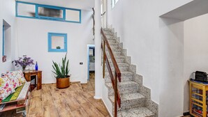 A staircase with a wooden handrail leading to a second floor, a wooden bench with colorful cushions, a potted plant, and a small table with a vase. - Vacation Home 'Casa Bene' with Mountain View, Wi-Fi and Air Conditioning (Guimar)