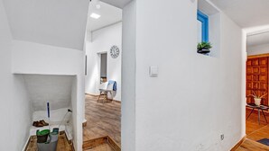 A hallway with a white wall, a blue-framed window, a clock, and a wooden floor. - Vacation Home 'Casa Bene' with Mountain View, Wi-Fi and Air Conditioning (Guimar)