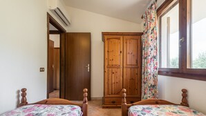 Een slaapkamer met twee houten bedden, een houten kast en een raam met gordijnen.