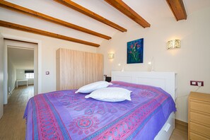 Ein Schlafzimmer mit einem Bett, Holzbalken an der Decke, einem Gemälde und einem Nachttisch.