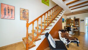 Eine Treppe mit Holzspindeln, ein Essbereich mit Tisch und Stühlen sowie ein Bücherregal.