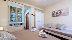 Een slaapkamer met een bed, een bank, een kast met glazen deuren en een schilderij aan de muur.
