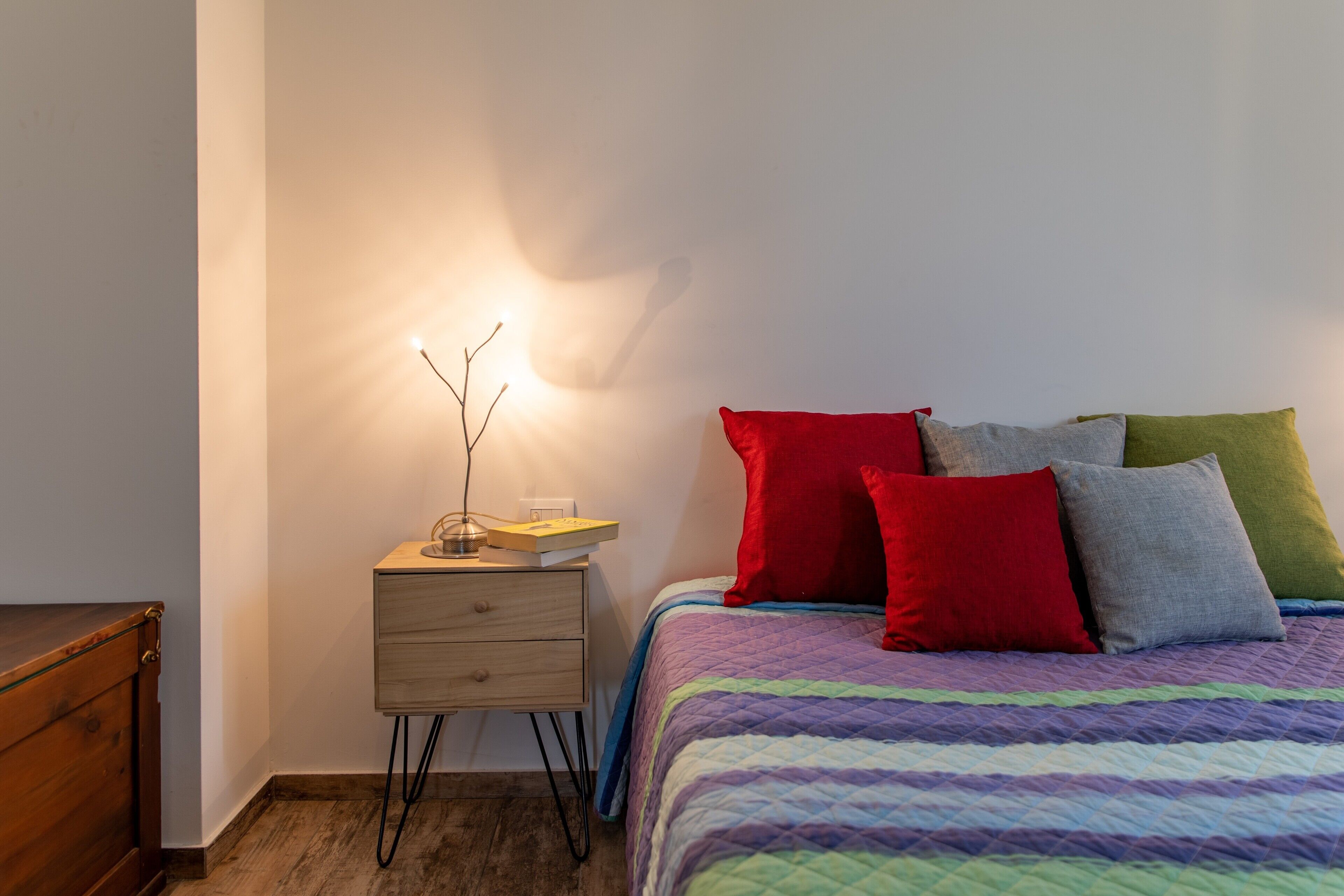 A bedroom with a bed, a bedside table with a lamp, and a nightstand.