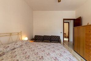 A bedroom with a bed, a sofa, a wardrobe, and a lamp.