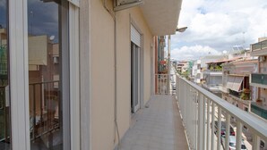 Ein schmaler Balkon mit Geländer, einer Tür und Blick auf benachbarte Gebäude.
