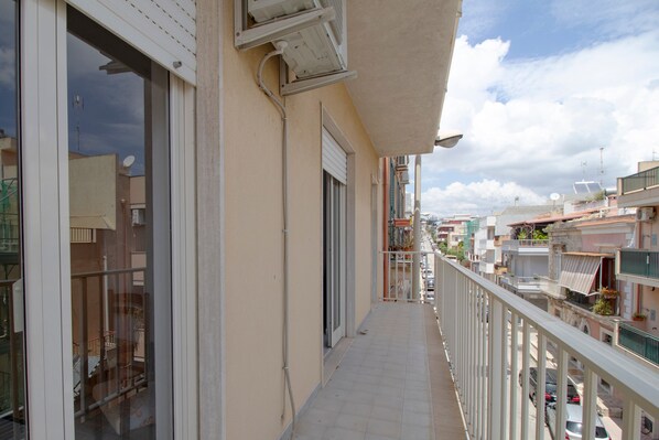 A narrow balcony with a railing, a door, and a view of adjacent buildings.
