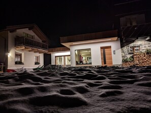En moderne bygning med balkon, et stort spejl der afspejler indretningen, og en stenvæg med et vindue.